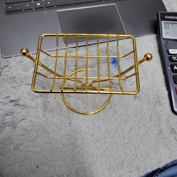 The Golden Wire Soap Stand (Rectangular) is a stylish and functional accessory for your bathroom or kitchen. Crafted from durable and elegant golden wire, this rectangular soap stand offers a sleek and modern design. It provides a convenient and hygienic solution for keeping your soap elevated and dry, preventing it from becoming soggy and extending its lifespan. The open wire construction allows for efficient drainage, promoting air circulation around the soap. This stand not only enhances the aesthetic of your space but also helps maintain the cleanliness and longevity of your soap.